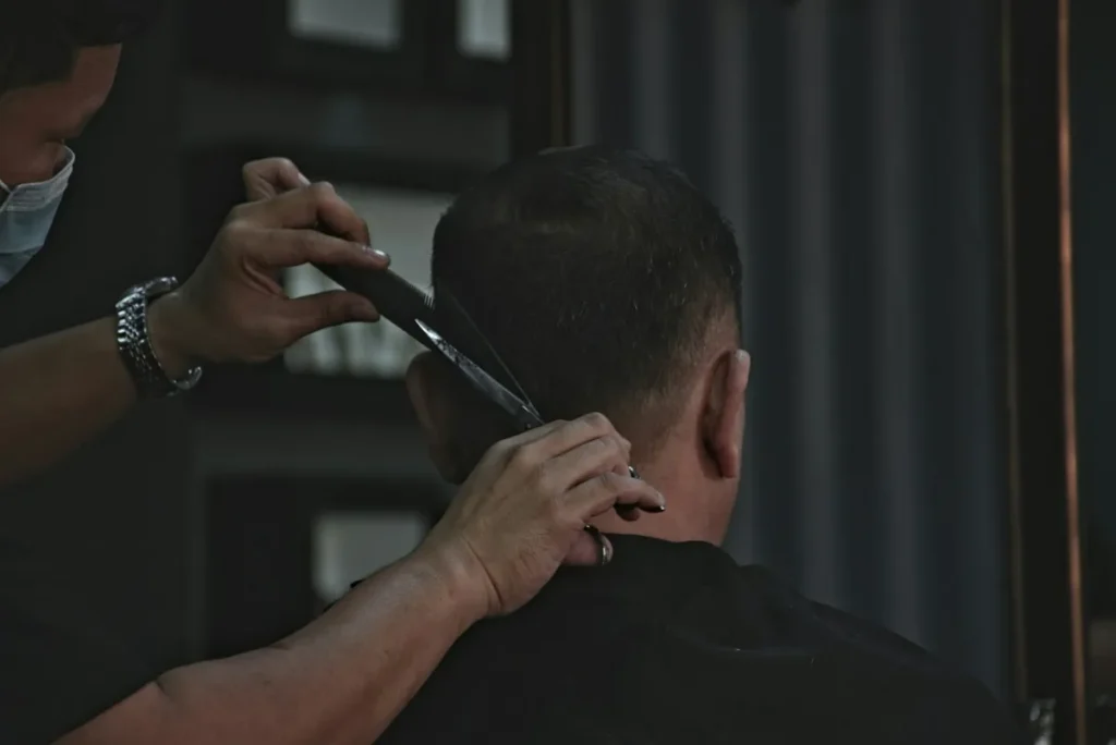 Barber trimming the back of a man's hair to a short cut